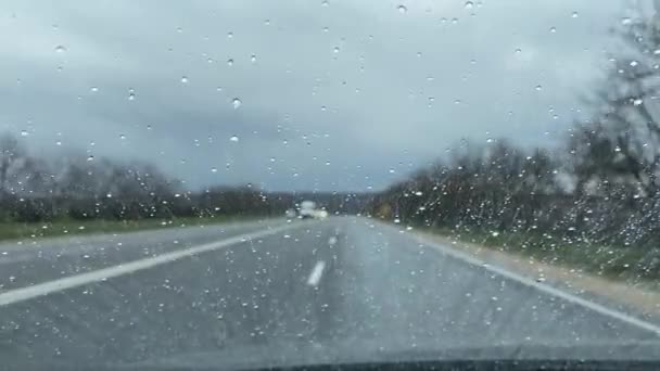 不安定なカメラだ 渋滞時の雨滴の車の窓からの自然の景色市内のぼやけたアスファルトの道路を背景に — ストック動画