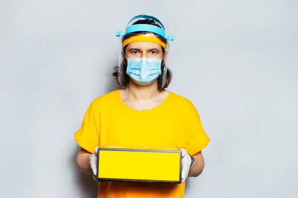 Retrato Jovem Entregador Segurando Uma Caixa Amarela Usando Máscara Médica — Fotografia de Stock