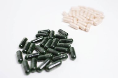 Beyaz arka planda izole edilmiş yeşil ve sarı kapsül haplarının yakın çekimi.