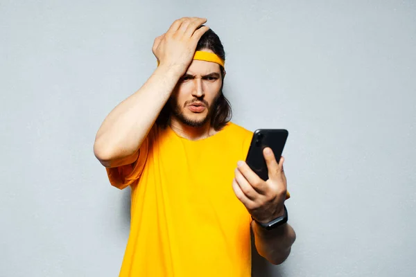 Retrato Estudio Joven Sorprendido Mirando Smartphone Vestido Amarillo Sobre Fondo — Foto de Stock
