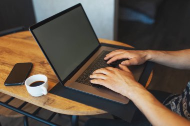 Dizüstü bilgisayarda çalışan erkeklerin yakın plan fotoğrafları, ahşap masada akıllı telefon ve kahve fincanı..