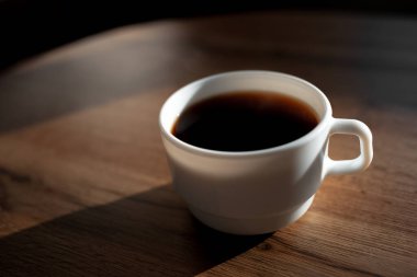 Ahşap masada beyaz seramik kahve fincanı yakın plan..