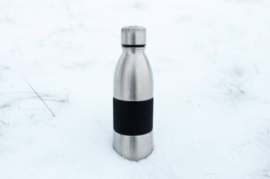 Çelik, yeniden kullanılabilir termo su şişesinin karla yakın çekimi..
