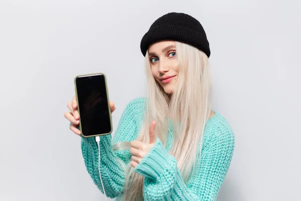 Retrato Menina Bonita Loira Mostrando Smartphone Polegares Fundo Branco Vestindo — Fotografia de Stock