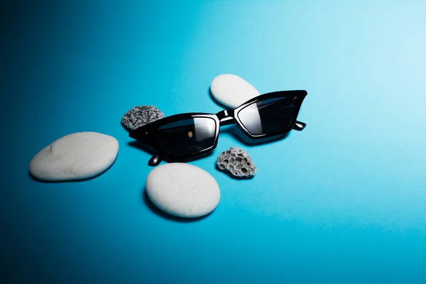 Detailní Záběr Moderní Sluneční Brýle Blízkosti Bílých Šedých Kamenů Modrém — Stock fotografie