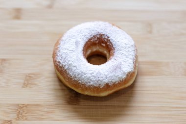 Tahta masanın üzerindeki şekerli pudralı çöreğin yakın plan fotoğrafı.. 