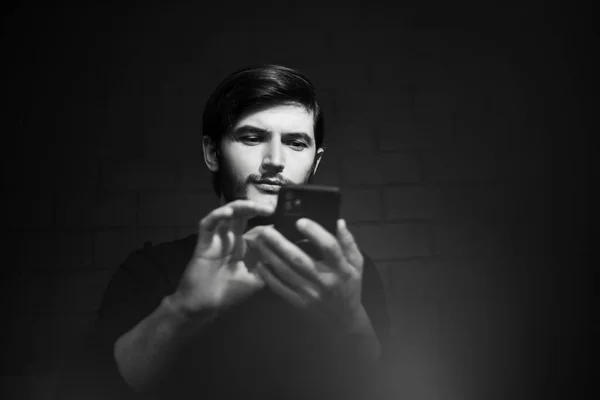 Young man typing on smartphone, black and white photo.
