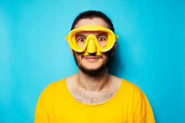 Mavi arka planda yüzmek için sarı Google takan genç dalış yapan adamın portresi.