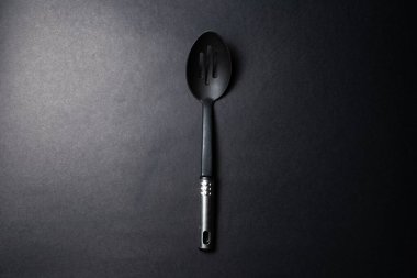 Büyük siyah plastik kaşığın yakın plan stüdyo fotoğrafı, karanlık masanın üzerinde..