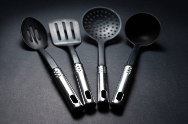 Krom saplı siyah plastik mutfak aletlerinin yakın plan fotoğrafı..