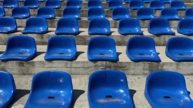 İnsan yok. Spor stadyumunun mavi boş plastik koltukları.
