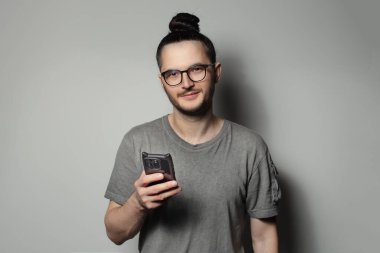 Stüdyo portresi, elinde akıllı telefon tutan saçları olan genç bir adam..