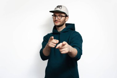 Genç mutlu adamın stüdyo portresi beyaz arka plandaki kamerayı işaret ediyor..