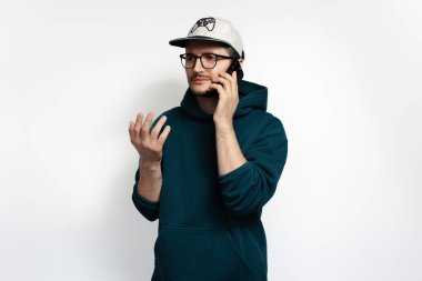 Akıllı telefonuyla konuşan kafası karışmış genç adam beyaz arka planda izole edilmiş..