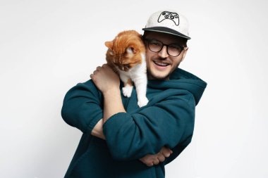 Kırmızı beyaz kedisiyle oynayan mutlu genç adam. Beyaz arkaplanda izole.