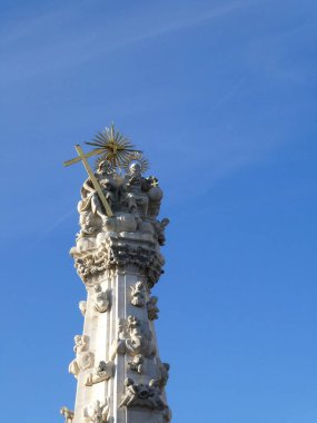 Macaristan, Budapeşte 'deki Kutsal Üçleme Sütunu. 14 metre boyunda altıgen bir dikilitaş, bir heykel grubuyla çevrelenmiş, Baba (küre ile kutsanmış bir jest yapan yaşlı adam), Oğul (haç tutan İsa) ve Kutsal Ruh 'u (ortada bir güvercin) gösteren bir heykel.