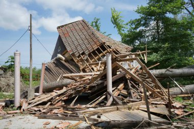 Kasırgadan zarar görmüş bir ev. Önünde devrilmiş bir ağaç var.