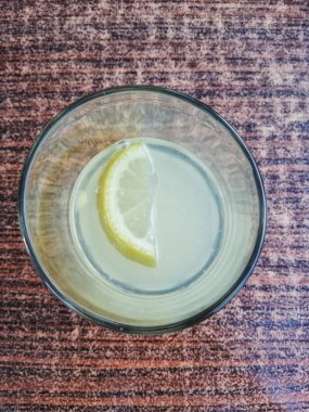 Masanın üstünde cam içinde limon dilimi.