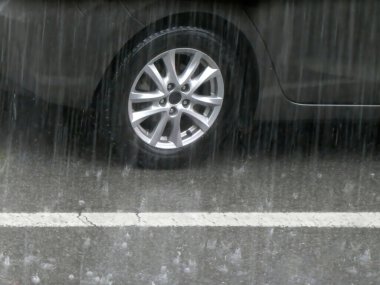 Yağmurlu havada asfalt yolda giden araba tekerleği.