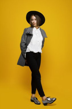 Şapkasını ve ceket ile sarı bir arka plan üzerinde kız modeli maliyeti