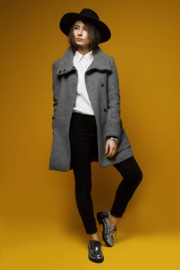 Şapkasını ve ceket ile sarı bir arka plan üzerinde kız modeli maliyeti