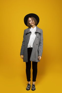 Şapkasını ve ceket ile sarı bir arka plan üzerinde kız modeli maliyeti