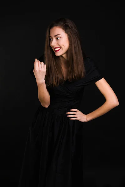 Chica de pie en un vestido negro es riendo y mirando hacia otro lado — Foto de Stock