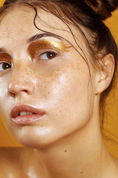 Retrato de uma menina bonita em um fundo amarelo com o efeito da pele molhada — Fotografia de Stock