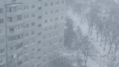 Şehre bakan üst katın penceresinden bak. Kış, kar yağıyor.