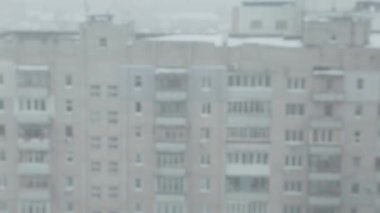 Şehre bakan üst katın penceresinden bak. Kış, kar yağıyor.