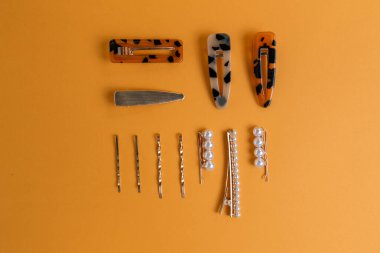 Sarı arka planda bir saç stilisti için aksesuar ve saç tokaları kompozisyonu