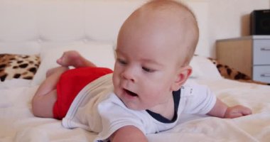 Erkek bebek kalkmaya çalışırken bir yatağa yatıyor