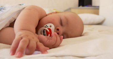 Bebek emziği ile bir yatak üzerinde uyuyor