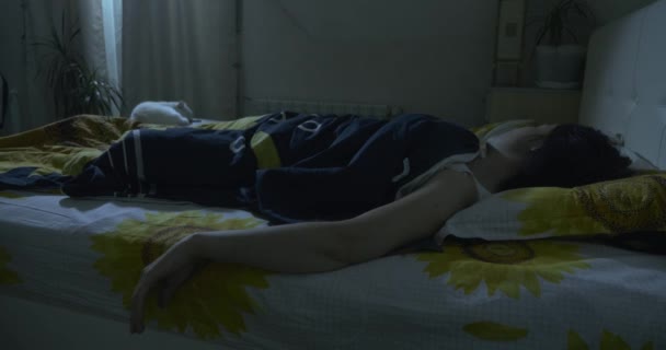 白猫睡在年轻女人旁边的床上 夜间卧房 — 图库视频影像