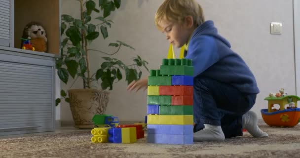 幸せな小さな子供がおもちゃで遊ぶ部屋のカーペットフロアのレンガ造りのコンストラクター — ストック動画