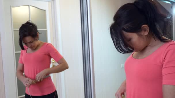 Женщина Проверяет Своё Тело Помощью Измерительной Ленты Перед Зеркалом Дома — стоковое видео