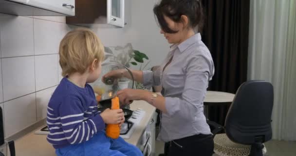 Lindo Niño Pequeño Come Zanahoria Grande Sentado Mesa Cocina Mientras — Vídeo de stock