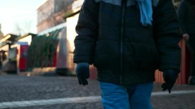 Kayıp çocuk Noel pazarında tek başına dolaşıyor ve etrafa bakıyor. Kış tatilleri. Akşam Şehri. 2x Yavaş çekim 60 FPS 4K