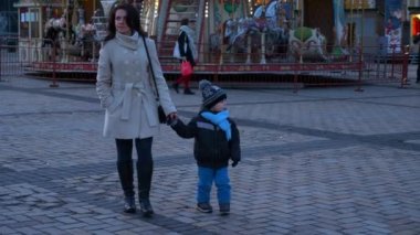 Noel Pazarı 'nda Yürüyen ve Etrafa Bakınan Çocuklu Anne. Kış tatilleri. Evening City Caddesi. 2x Yavaş çekim 60 fps 4K