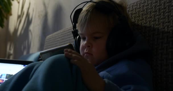 近视儿童脸 小男孩在智能手机上观看卡通片媒体游戏 Toddler坐在沙发上 — 图库视频影像