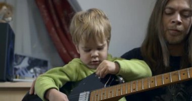 Genç rockçı müzisyen çocuk gitar çalmayı öğretiyor. Baba ve Oğul Müzik Ders 4K