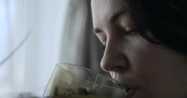 Mutlu kadın pencereye bakarken çay içmekten zevk alıyor. Evde Oda 'da oturmak. Yakın plan Kadın Yüzü