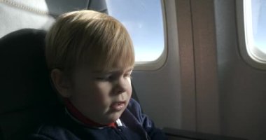 Ufaklık uçakta yolcu koltuğunda Menü Kitabı 'nı okuyor. Yolcu Jeti 4K 'da Menü Seçimi