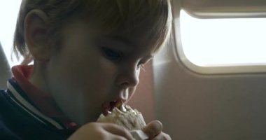 Uçuş sırasında uçakta Lezzetli Peynirli Sandviç Yiyen Aç Küçük Çocuk