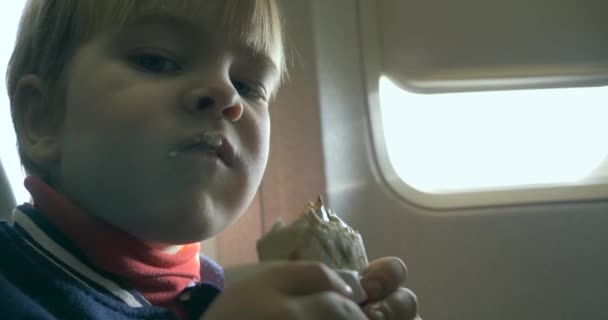 Éhes kisfiú eszik ízletes sajt tekercs szendvics a fedélzeten a repülőgép repülés közben