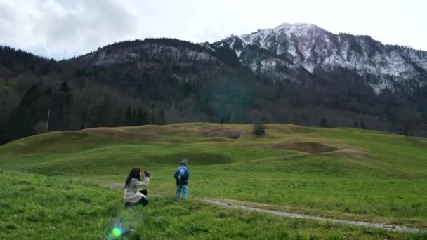 Matka Fotí Fotky Smartphone Malého Dítěte Trávě Blízkosti Scenic Mountain — Stock video