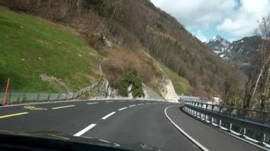 Dağ yolu boyunca arabayla seyahat etmek. POV ön cam kapüşonlu kapüşonlu fotoğraf İsviçre Alpleri 'nde. İlkbahar İsviçre Avrupa. Yavaş çekim
