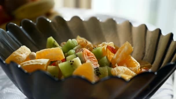 Närbild Jordnötter Fall Fruktsallad Kiwi Orange Glas Skål Vitt Bord — Stockvideo