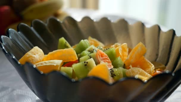 Close Raisins Queda Salada Frutas Laranja Kiwi Tigela Vidro Mesa — Vídeo de Stock