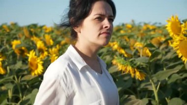 Genç kadın ayçiçeği tarlasına bak. Kadın Tarım İşçisi Geleceğin Ürünlerini Denetliyor. Yaz sabahı. 2x Yavaş çekim 60fps 4K